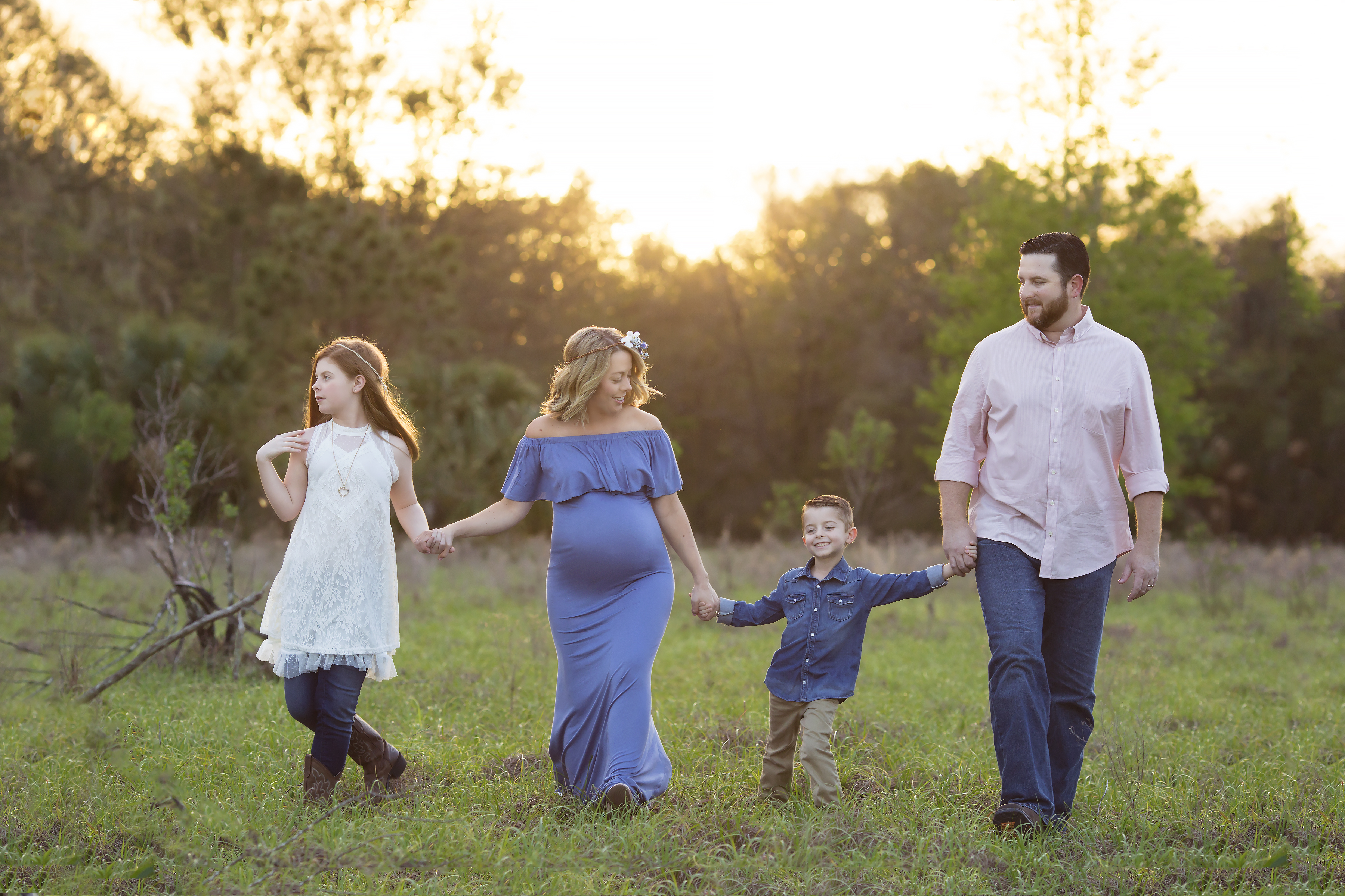 Family walking through a field during a maternity photography session in Lithia Florida